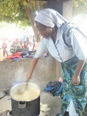 A canossiaan sister mixes the nsima in a campfire pot
